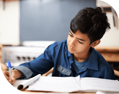Young boy studying in front of open book.