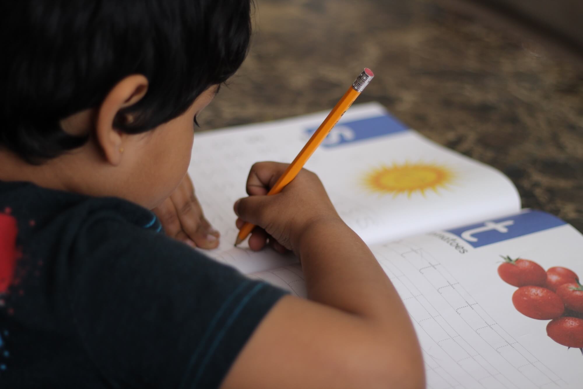 Over the shoulder shot of child doing his homework.