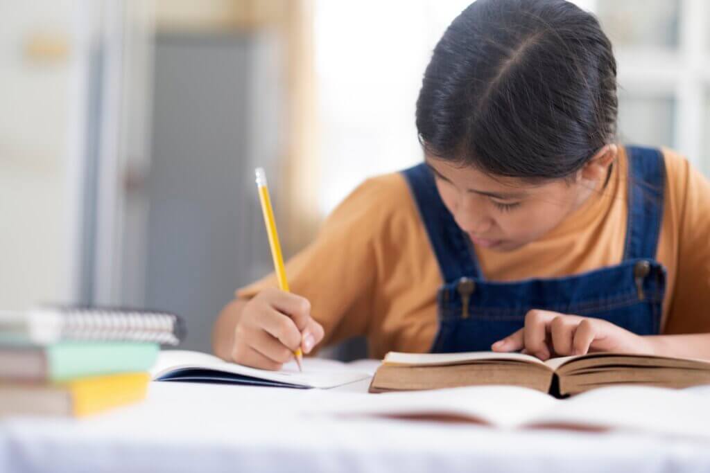 Asian girl reading and doing homework at her home