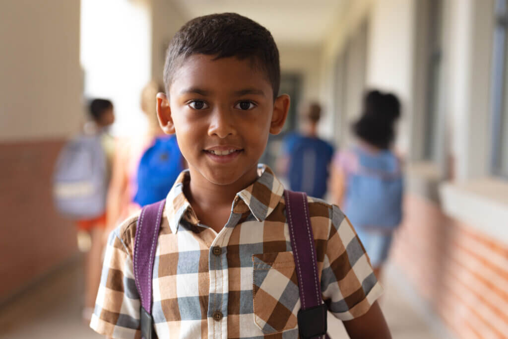 Portrait of smiling biracial elementary schoolboy standing in corridor