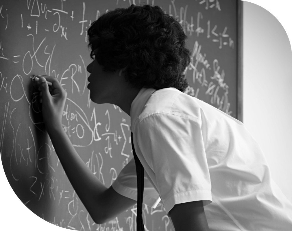 School student intently solving math problem on black board.