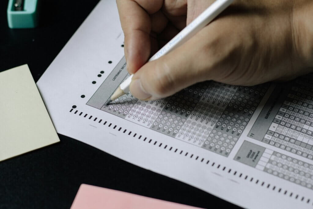 Student filing out objective competitive exam with pencil.