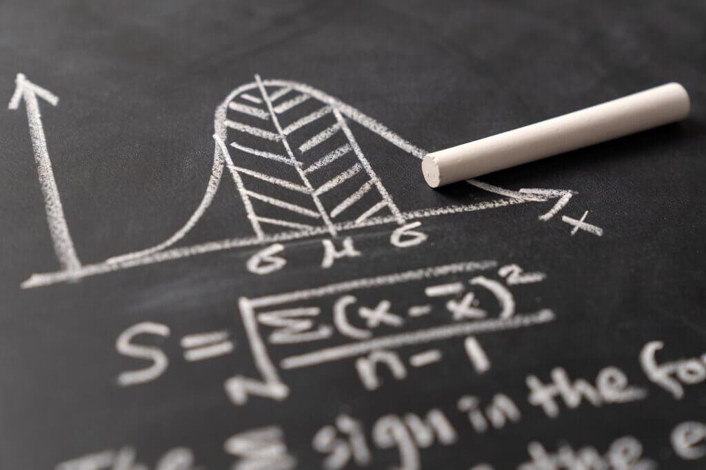 Bell curve graph and standard deviation formula is drawn on blackboard to illustrate data distribution and mathematic concept